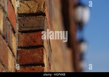 Red bricks bright with sunlight focused foreground with blurry streetlights and blue sky in background Stock Photo