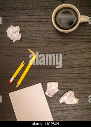 Dark surface, paper wads, broken pencil, coffee, frustration Stock Photo