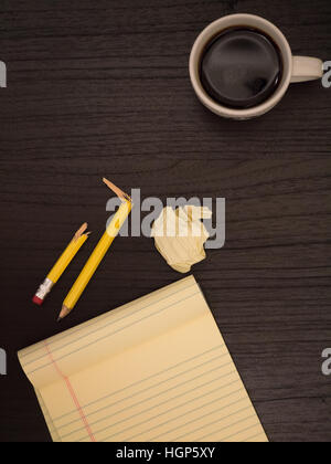 Dark surface, yellow, paper wads, broken pencil, coffee, frustration Stock Photo