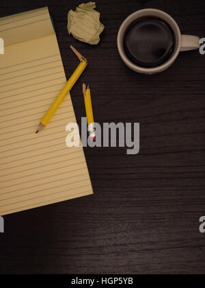 Dark surface, yellow, paper wads, broken pencil, coffee, frustration Stock Photo