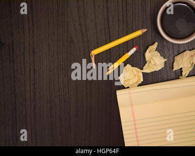 Dark surface, yellow, crumpled paper broken pencil, coffee, frustration Stock Photo