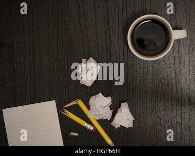 Dark surface, white,crumpled paper broken pencil, coffee, frustration Stock Photo