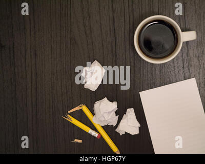 Dark surface, white,crumpled paper broken pencil, coffee, frustration Stock Photo