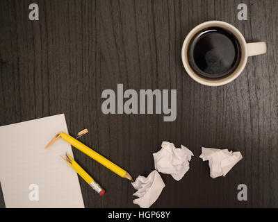 Dark surface, white,crumpled paper broken pencil, coffee, frustration Stock Photo