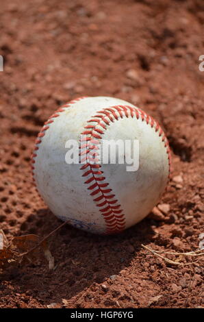 An old baseball in the dirt on a playing field Stock Photo