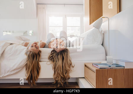 Young woman and a girl lying on bed. Mother and daughter in bedroom.