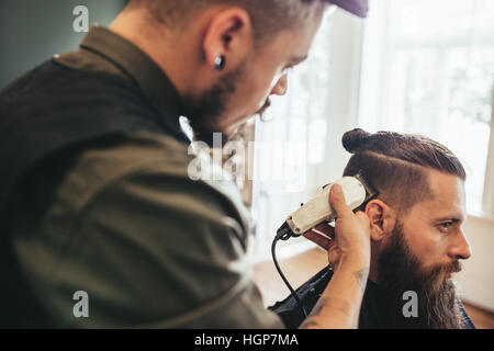 Beard man getting haircut at barber shop. Hairdresser cutting hair of customer at salon. Stock Photo