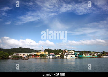 Cruising past the village & in to the port at Roatan Island, Honduras, Central America, Caribbean. Stock Photo