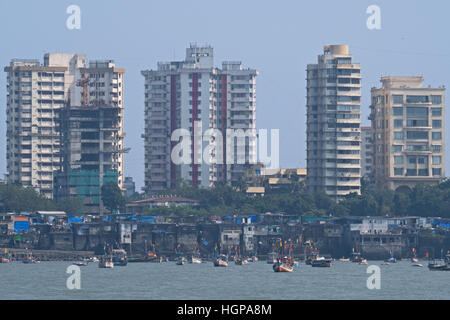 Fishing boats moored in front of traditional housing in the district of Colaba in Mumbai, with modern tower blocks behind them Stock Photo