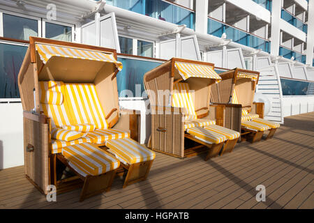 Roofed wicker beach chairs on the deck of a cruise ship. Stock Photo