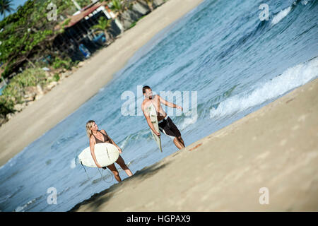 Surfers walking on the beach, Isabela, Puerto Rico Stock Photo