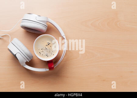 Headphones and coffee cup on office wooden desk table. Music concept. Top view with copy space Stock Photo