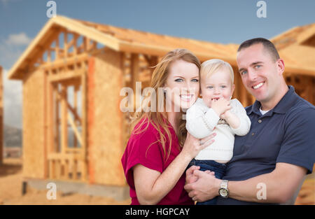 Happy Young Military Family Outside Their New Home Framing at the Construction Site. Stock Photo