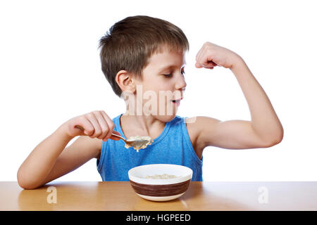 Happy boy eating porridge at the table isolated white Stock Photo