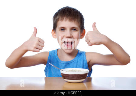 Happy boy eating porridge at the table isolated white Stock Photo