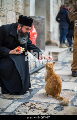 Pilgrim and cat in front of Holy Sepulcher church, Jerusalem, Israel. Stock Photo