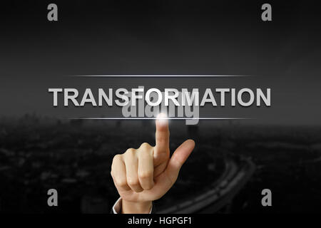 business hand clicking transformation button on black blurred background Stock Photo