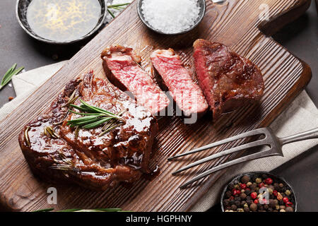 Grilled ribeye beef steak, herbs and spices on cutting board Stock Photo