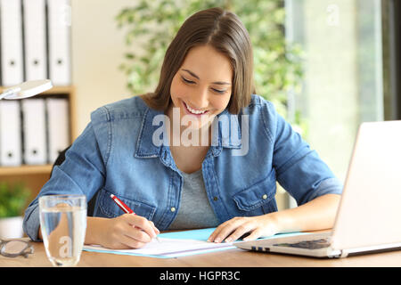 Happy freelance signing or filling form in a desktop at office Stock Photo