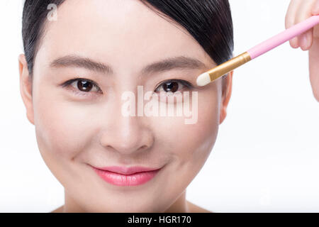 Portrait of young smiling woman using eyeshadow brush Stock Photo