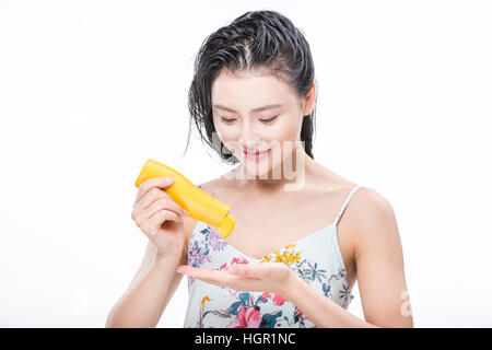 Portrait of young woman with wet hair using sunscreen Stock Photo