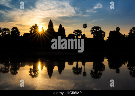 Angkor Wat temple at dramatic sunrise sunburst reflecting in water Stock Photo