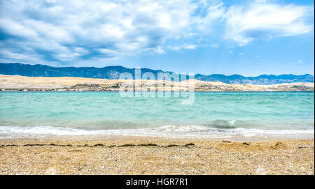 Strong wind bura is hitting coast of island Pag, making waves and splashes. Mountains Velebit in the background. Power and destructive force of wind. Stock Photo