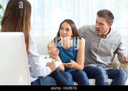 Angry couple speaking to a marriage counselor during therapy on a sofa in the living room of a house Stock Photo