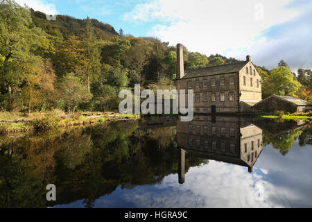 The Gibson Mill reflects in the water on a colourful and sunny autumn day at Hardastle crags near Hebden Bridge in West Yorkshire. Stock Photo