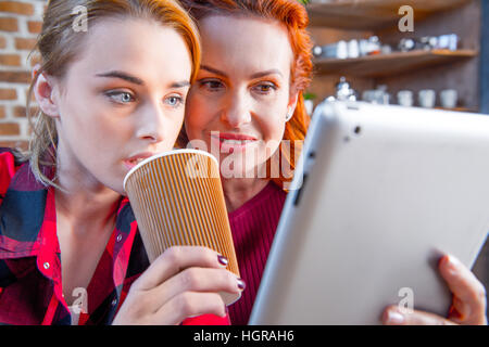 Two women using digital tablet and drinking tea at home Stock Photo