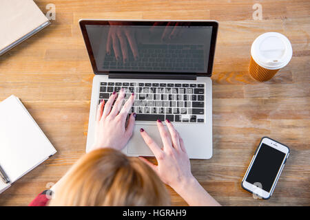 Top view of young woman using laptop sitting at the table Stock Photo