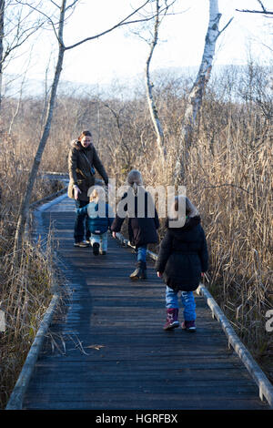 Mother & 3 children three kids daughters on walkway pathway foot path footpath Marais de Lavours National Nature Reserve. France Stock Photo