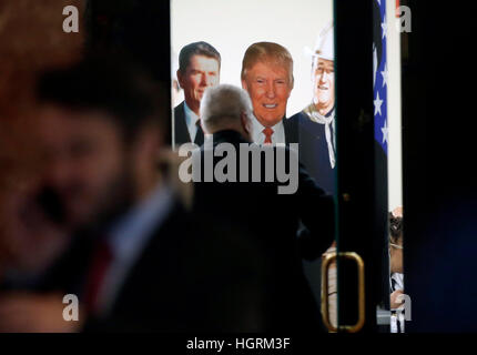 New York, USA. 11th Jan, 2017. A man enters a room decorated with a Ronald Regan, Donald Trump and John Wayne cardboard cutout/posters in Trump Tower on January 11, 2017 in New York, USA. U.S. President Elect Donald Trump is still holding meetings upstairs at Trump Tower as he continues to fill in key positions in his new administration. Credit: John Angelillo/Pool via CNP - NO WIRE SERVICE - Photo: John Angelillo/Pool via CNP/dpa/Alamy Live News Stock Photo