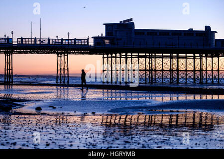 Worthing, West Sussex, UK. A solitary man walks along the beach under Worthing Pier as the day breaks on a clear, cold morning of 13/01/2017. Much of the rest of the UK is experiencing harsh winter weather with snow, ice and strong winds predicted in many areas on the country. Picture by © Julie Edwards/Alamy Live News Stock Photo