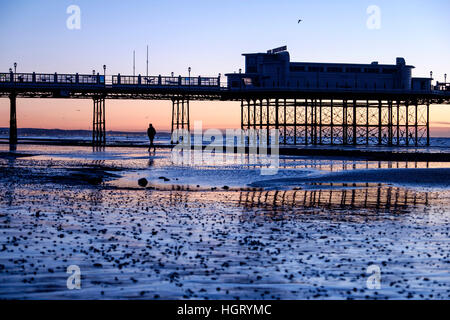 Worthing, West Sussex, UK. A solitary man walks along the beach under Worthing Pier as the day breaks on a clear, cold morning of 13/01/2017. Much of the rest of the UK is experiencing harsh winter weather with snow, ice and strong winds predicted in many areas on the country. Picture by © Julie Edwards/Alamy Live News Stock Photo