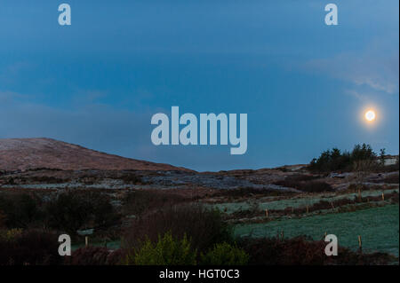 Ballydehob, Ireland. 13th Jan, 2017.  A 98% Waning Gibbous moon sets over Mount Corrin, near Ballydehob, West Cork after temperatures over-night plunged to below zero. This resulted in a heavy frost this morning, rendering the country roads extremely treacherous. ©Andy Gibson/Alamy Live News. Stock Photo