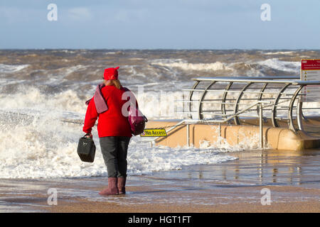 Blackpool, Lancashire, UK. 13th Jan 2017. UK Weather. Hardy souls brave the stormy waves on the Blackpool's famous Golden Mile sea front.  Strong gusty winds caused huge waves to crash against the sea defences.  Credit: MediaWorld Images/Alamy Live News Stock Photo