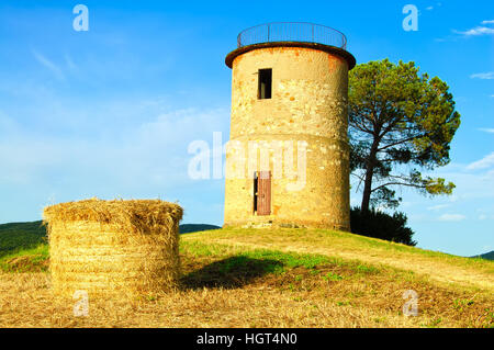 Tuscany, Maremma typical countryside sunset landscape with hill, tree, straw bales and rural tower. Stock Photo