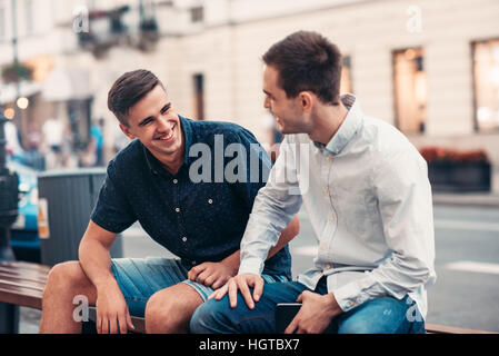 Friends talking together on a bench in the city Stock Photo