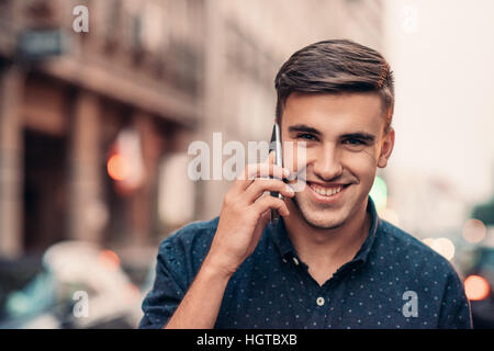 Smiling young man talking on his cellphone in the city Stock Photo