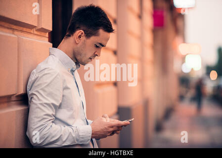 Handsome young man text messaging on a city street Stock Photo