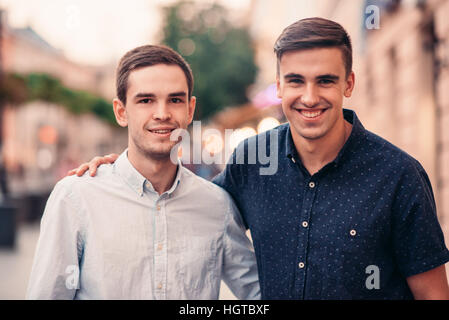 Two smiling friends standing together on a city street Stock Photo