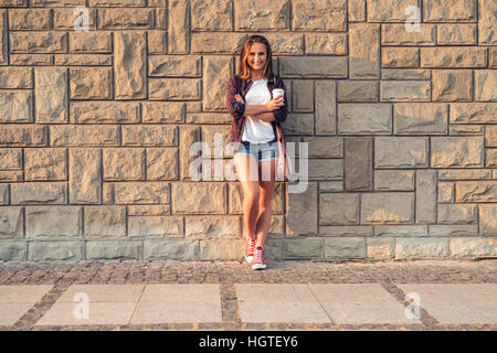 Smiling young woman leaning against a wall in the city Stock Photo