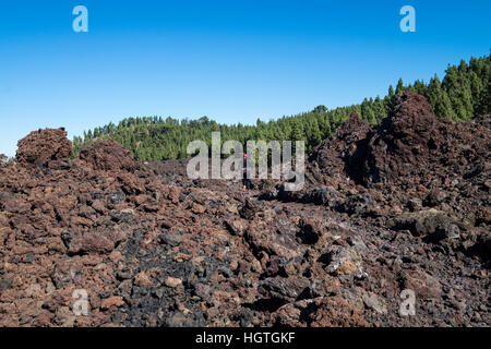 Runner crossing over the solidified lava flow from Chinyero volcano on Teide, Tenerife, Canary Islands, Spain Stock Photo