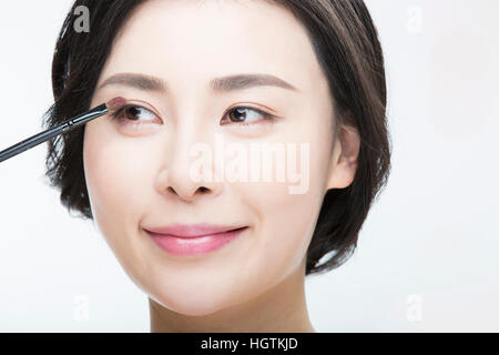 Portrait of young smiling woman with eyeshadow brush Stock Photo