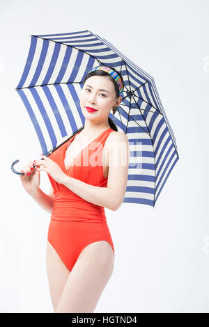 Young woman in orange swimsuit holding umbrella Stock Photo