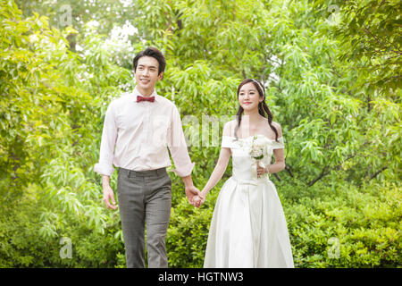 Young romantic wedding couple walking hand in hand outdoors Stock Photo