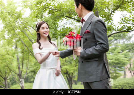 Young smiling wedding couple holding hands face to face outdoors Stock Photo