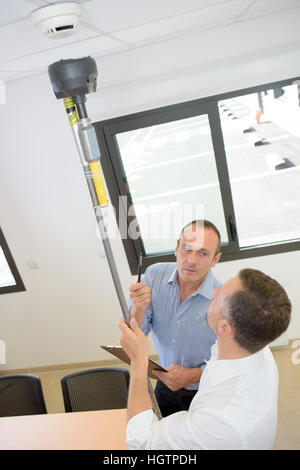 Man holding device for testing smoke alarms Stock Photo