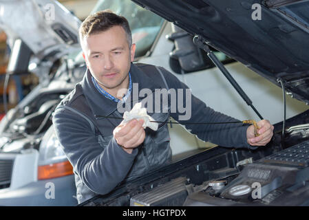 car mechanic replacing oil on engine in garage Stock Photo